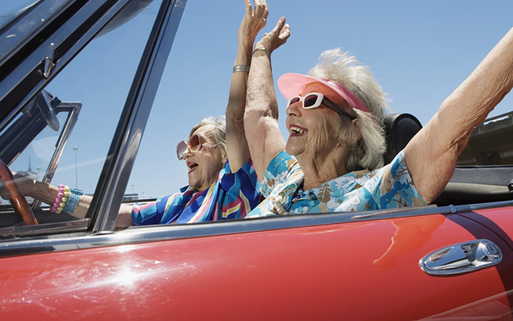 Two senior women in convertible car, arms outstretched, side view GDC-free-parking-for-80-800x500-1.jpg